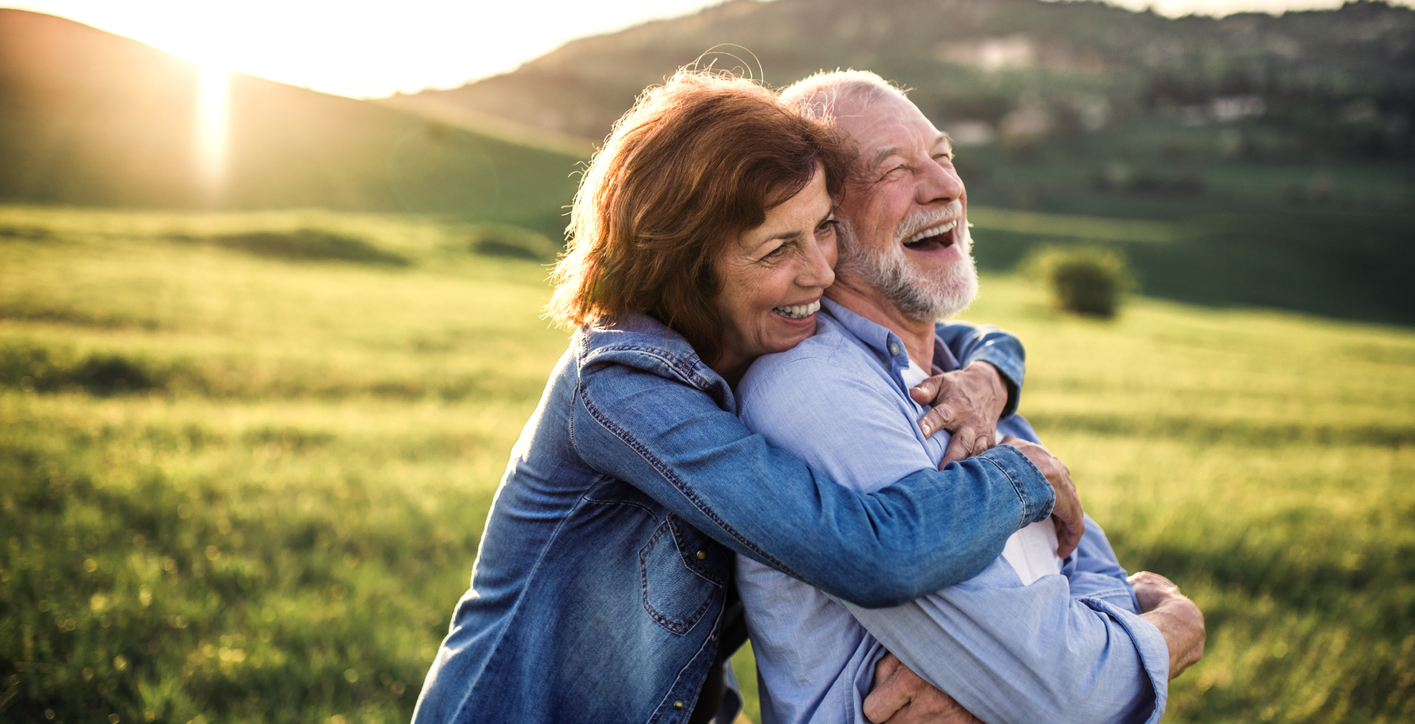 Imagen de Telefónica Tech donde se aprecia una pareja de personas mayores abrazándose y sonriendo en un entorno natural al atardecer.